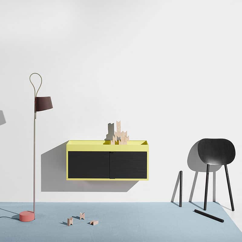 Modern home decor with a minimalist wall cabinet, unique chair, and floor lamp.
