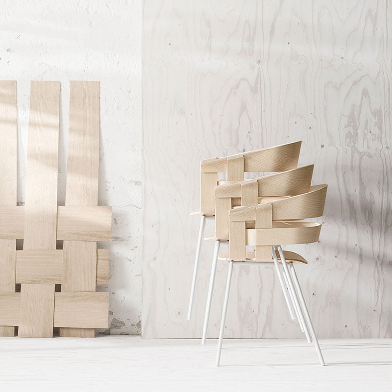 Modern woven wooden chairs stacked in a minimalist room with light wood accents.