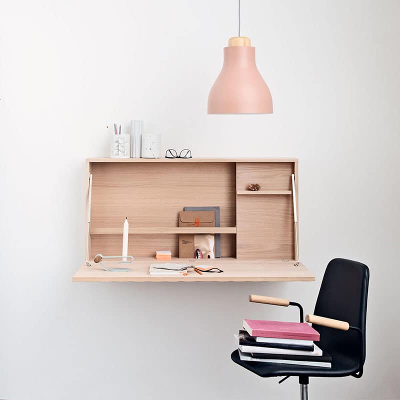 Modern wall-mounted desk with decorative accessories and a pendant light.