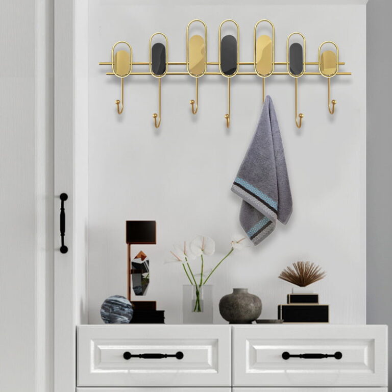 Modern wall decor with gold accents and hooks, featuring a towel and decorative items on a dresser.
