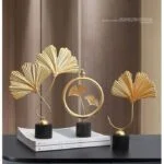 Elegant gold leaf sculptures on a modern blue cabinet, enhancing luxury home decor.