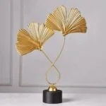 Gold decorative sculpture with fan-shaped leaves on a black base, modern home decor.