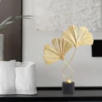 Modern luxury home decor with gold leaf sculpture and textured vase.