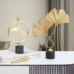 Gold decorative ornaments on a table, featuring leaf designs and modern home decor style.