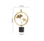 Gold decorative ornament with circular design and leaf motif on black base.