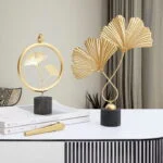 Modern luxury home decor with gold leaf sculptures on a table.