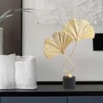 Modern luxury home decor with gold leaf sculpture and textured white vase.