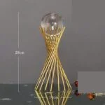 Modern gold decorative ornament with a glass sphere on a reflective surface.