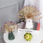 Elegant decorative ornaments with gold branches and purple accents on a table with books.