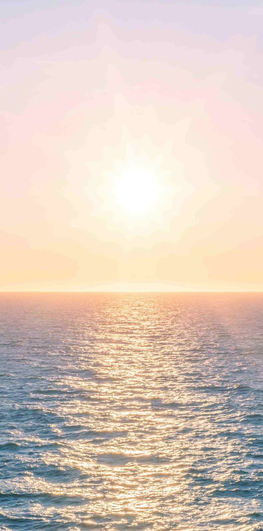 Sunset over ocean with warm colors and gentle waves.