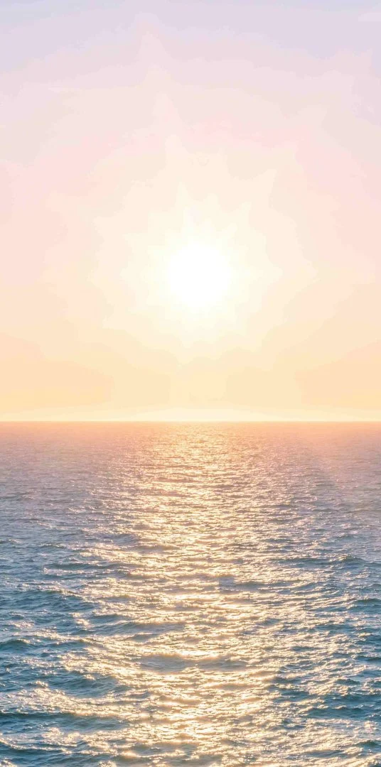 Sunset over ocean with warm colors and gentle waves.