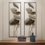 Modern metal wall art with leaf design and decorative vase on wooden table.