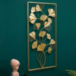 Gold metal wall art with leaf design on a teal wall, modern home decor.