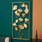 Gold metal wall art with leaf design on a green wall, modern home decor.
