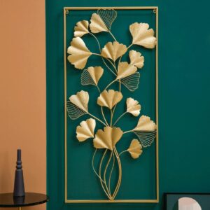 Gold metal wall art with leaf design on a teal and orange wall.