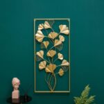 Gold metal wall art with leaf design on green wall, modern home decor.