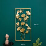 Gold metal wall art with leaf design on a green wall, modern home decor.