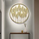 Modern gold metal wall art with leaf design in a circular frame, enhancing luxury home decor.