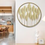 Modern gold leaf wall art in dining room with wooden decor and sculpture.
