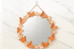 Round decorative wall mirror with butterfly accents, perfect for modern home decor.