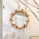 Round decorative wall mirror with butterfly accents, modern home decor.