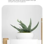 Modern white planter with green plant on a wooden shelf.