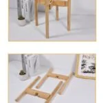 Collapsible wooden plant stand with books and a small potted plant on a white surface.