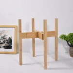 Modern wooden plant stand with framed art and decorative vase.
