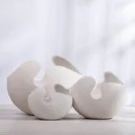 Modern white ceramic vases with abstract design on a light background.