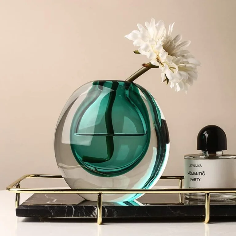 Elegant glass vase with flower on decorative tray, modern home decor.
