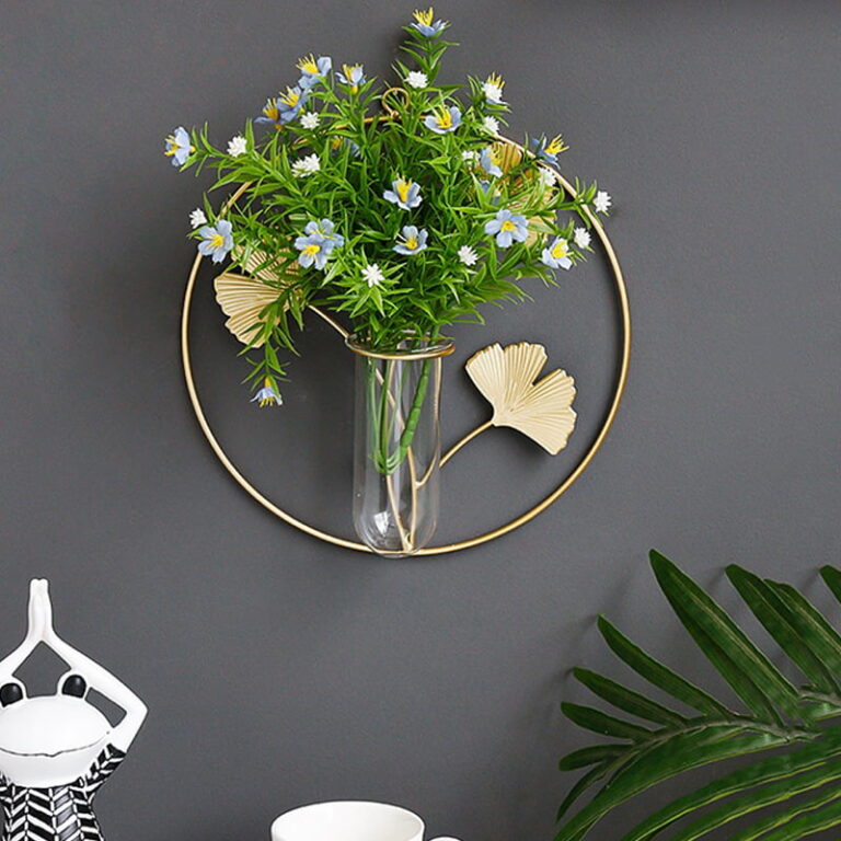 Modern wall decor with a circular metal frame and glass vase holding flowers.