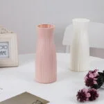 Elegant pink and white ceramic vases on a table with decorative flowers.
