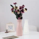Elegant pink and white ceramic vases with flowers on a modern table.