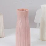 Pink ceramic vase on a white table, modern home decor accessory.