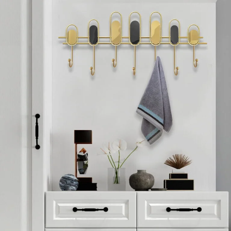 Modern wall decor with gold accents and hooks, featuring a towel and decorative items on a dresser.