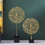 Gold decorative sculptures on black bases against a green wall, modern home decor.