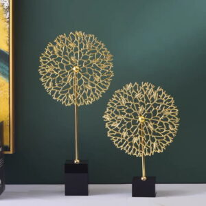 Gold decorative sculptures on black bases against a green wall, modern home decor.