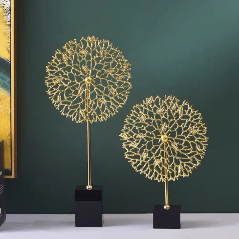 Gold decorative sculptures on black bases against a green wall, modern home decor.