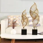 Modern gold sculptures on a table with a vase in a stylish living room.