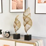 Modern gold decorative sculptures on a sideboard with framed wall art and a vintage clock.