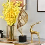 Modern home decor with gold sculpture, yellow flowers in vase, and decorative deer figurine.
