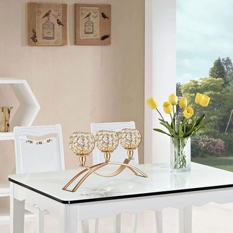 Elegant gold candle holder on a modern dining table with yellow tulips and wall art in the background.