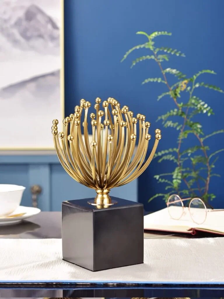 Gold decorative sculpture on black base in modern home setting.