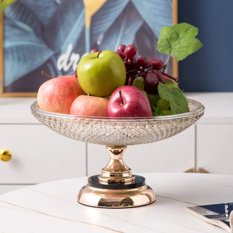 Elegant crystal fruit bowl on a gold stand with apples and grapes, modern home decor.