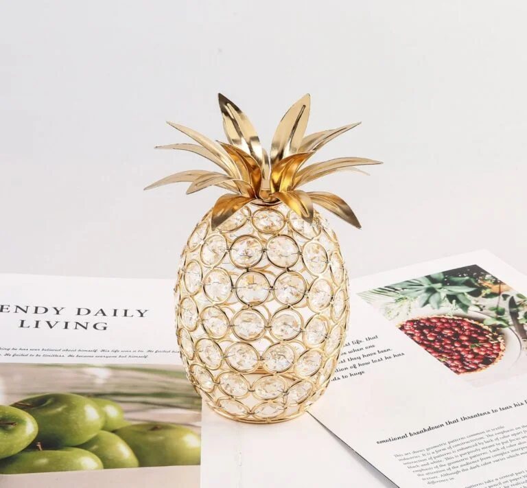 Gold pineapple decorative ornament with crystal accents on a table.