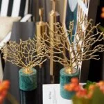 Gold decorative tree sculptures on green marble bases for modern home decor.
