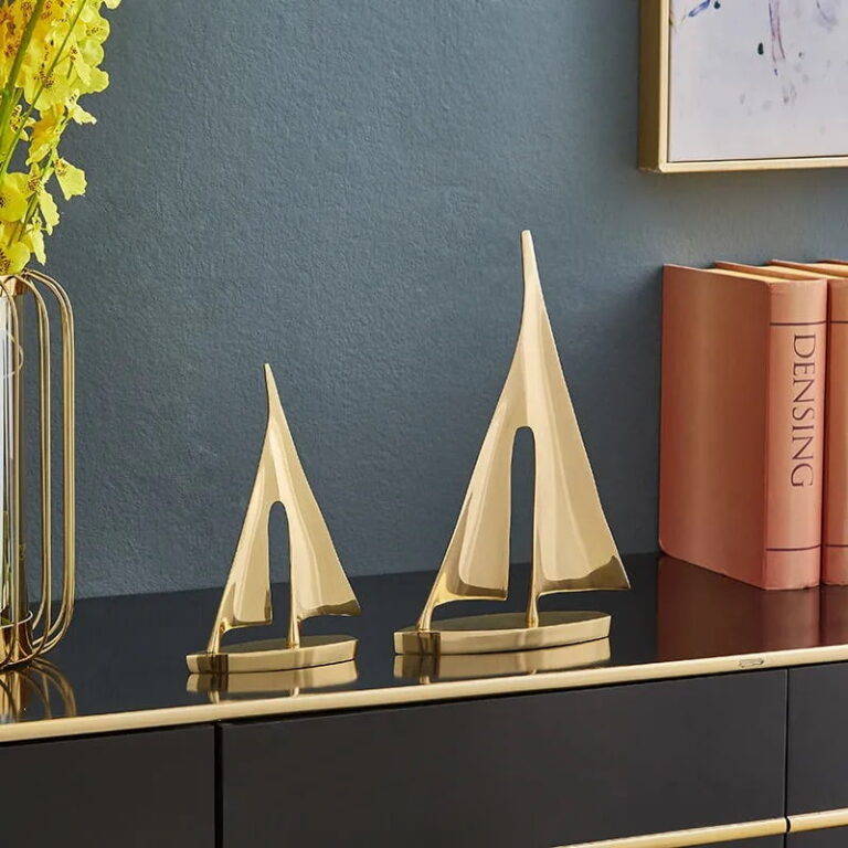 Gold sailboat sculptures on a modern black console with books and a decorative vase.