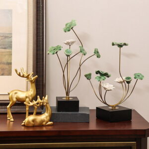 Elegant gold deer sculptures and green floral decorative ornaments on a wooden table.