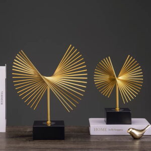Modern gold decorative sculptures on a table with books, ideal for luxury home decor.