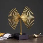 Modern gold decorative sculpture on a black base with a small gold bird figurine.